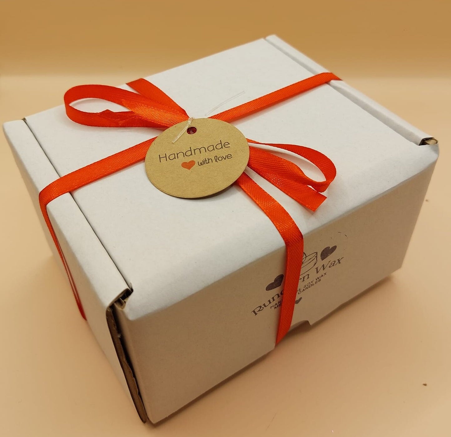 White box with a red ribbon and a round tag on a beige background
