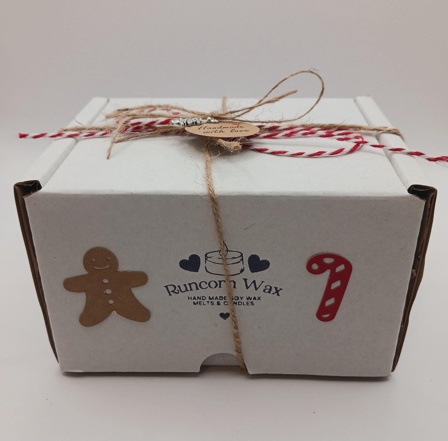 White gift box with Runcorn Wax branding, gingerbread man, candy cane, and heart designs on a white background.