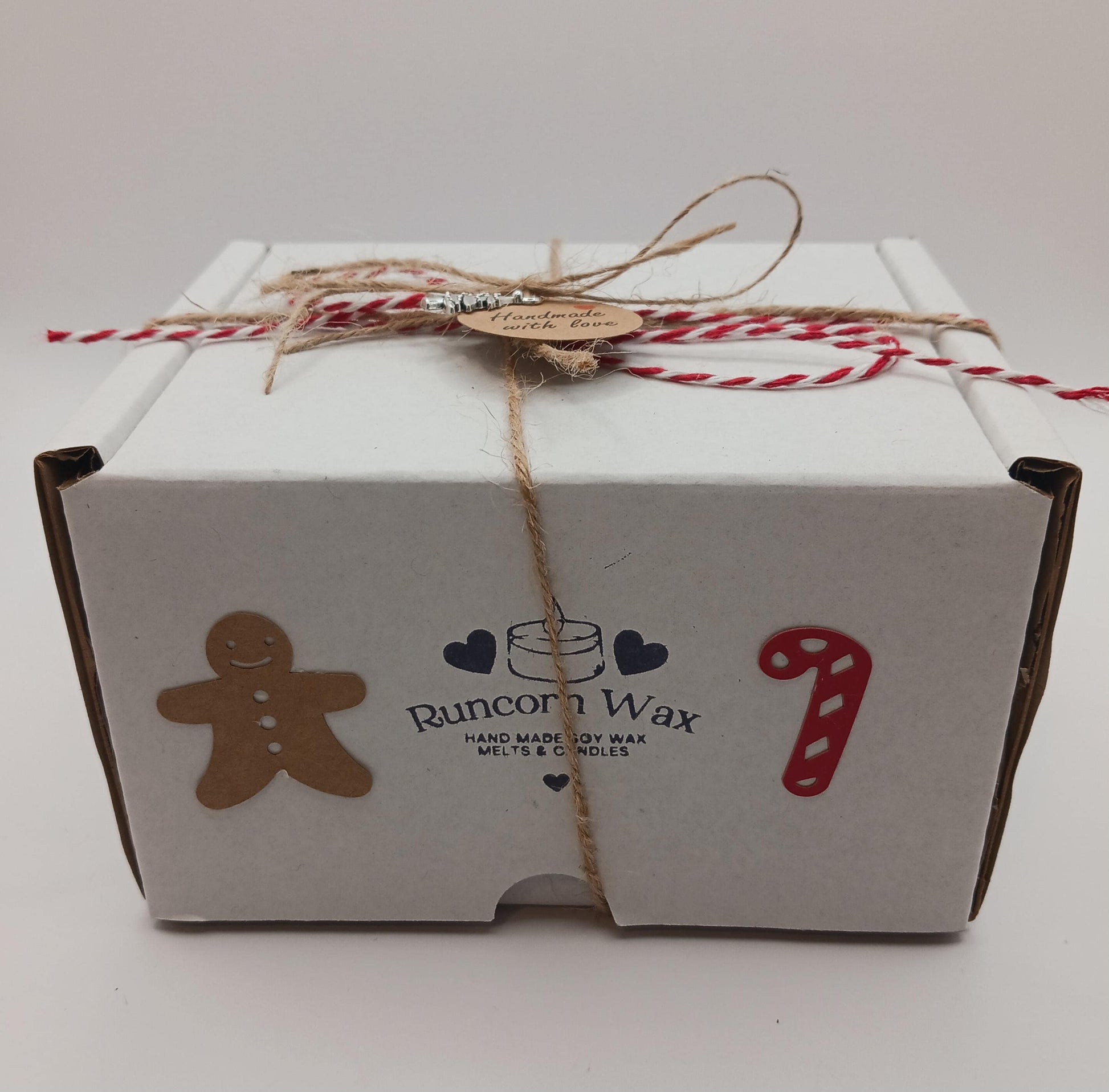 White gift box with Runcorn Wax branding, gingerbread man, candy cane, and heart designs on a white background.