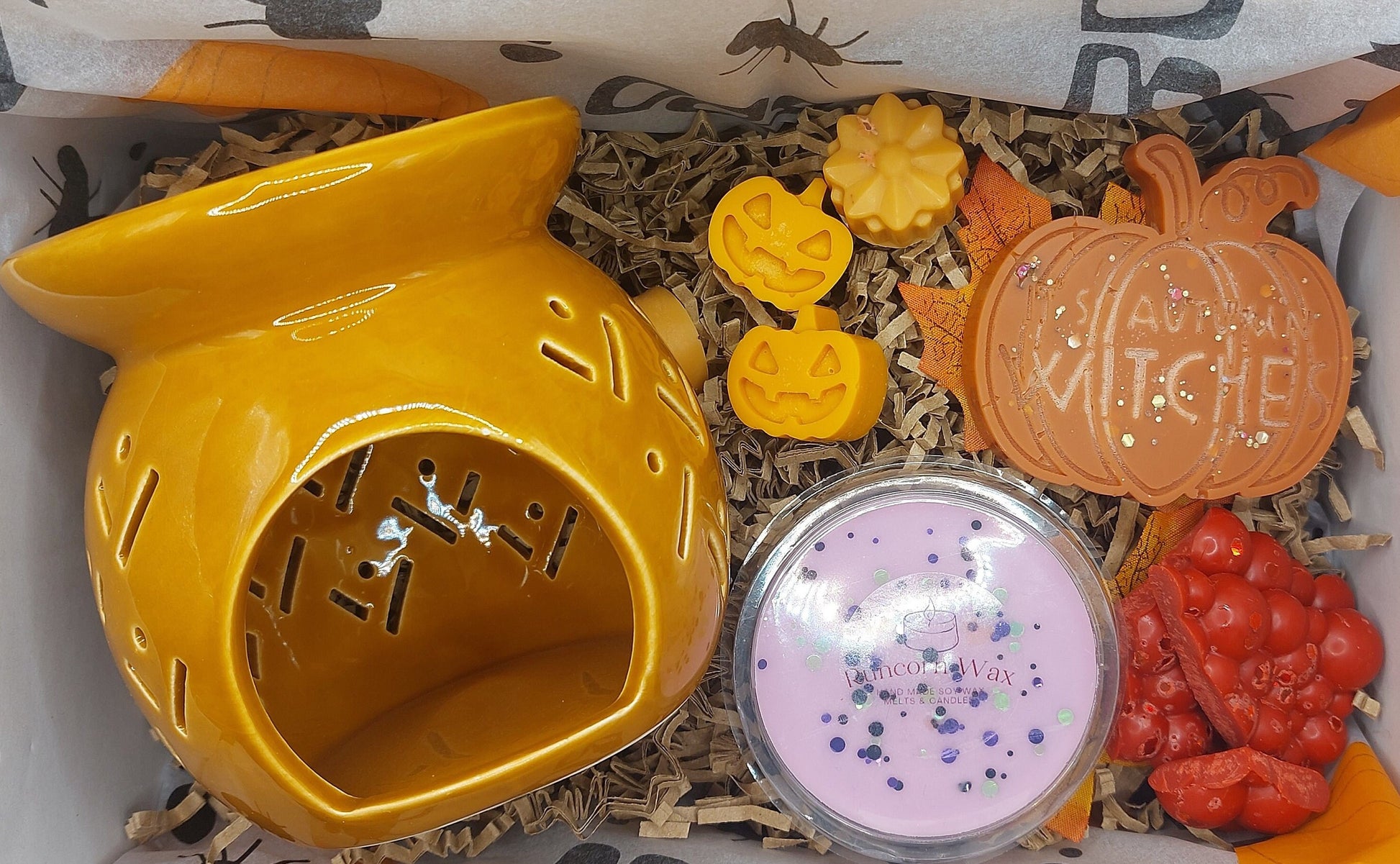 Decorative items including a yellow ceramic pumpkin, small pumpkins, and a round container with sprinkles on a textured surface.