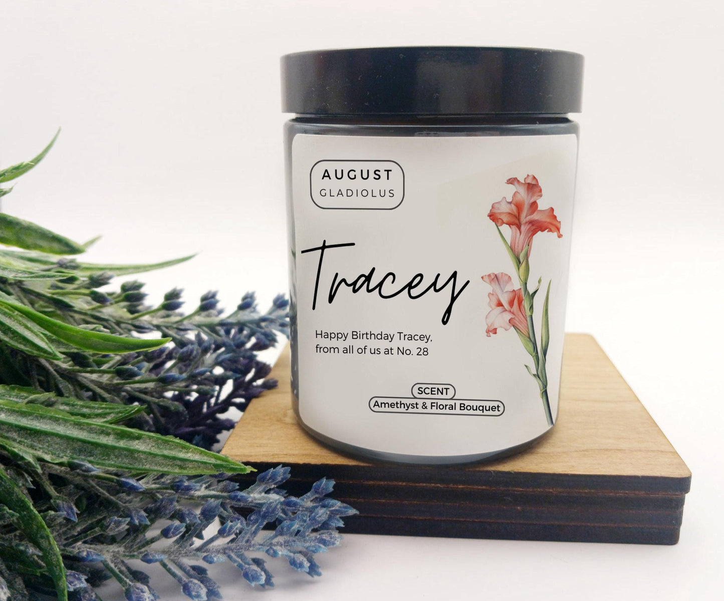 Candle jar with 'August Gladiolus' branding and floral design on a white background
