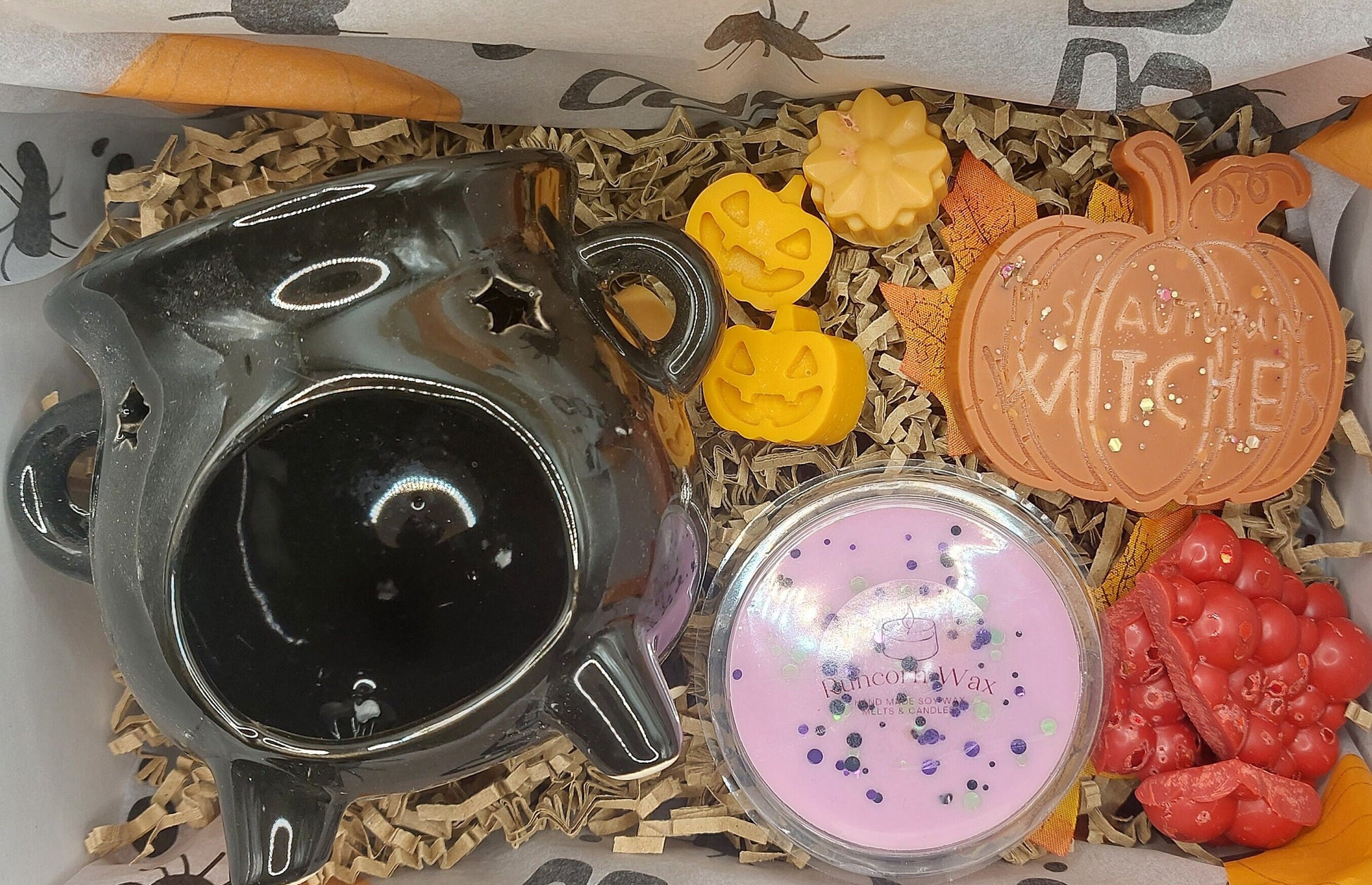 Decorative items including a black ceramic pot, colorful soap bars, and a pink container with glitter in a box.