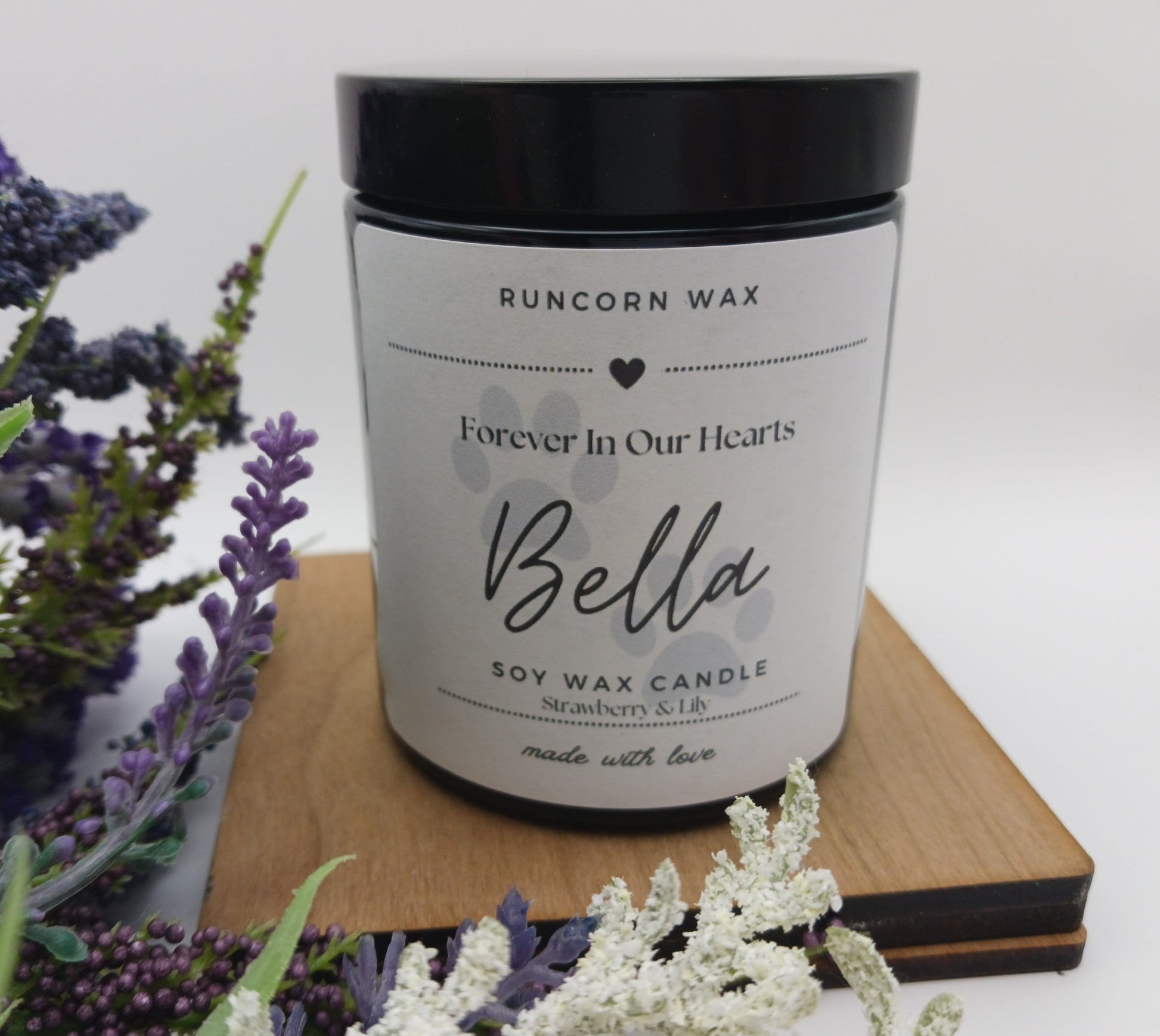 Soy wax candle labeled 'Bella' by Runcorn Wax on a wooden board with lavender flowers. pet loss