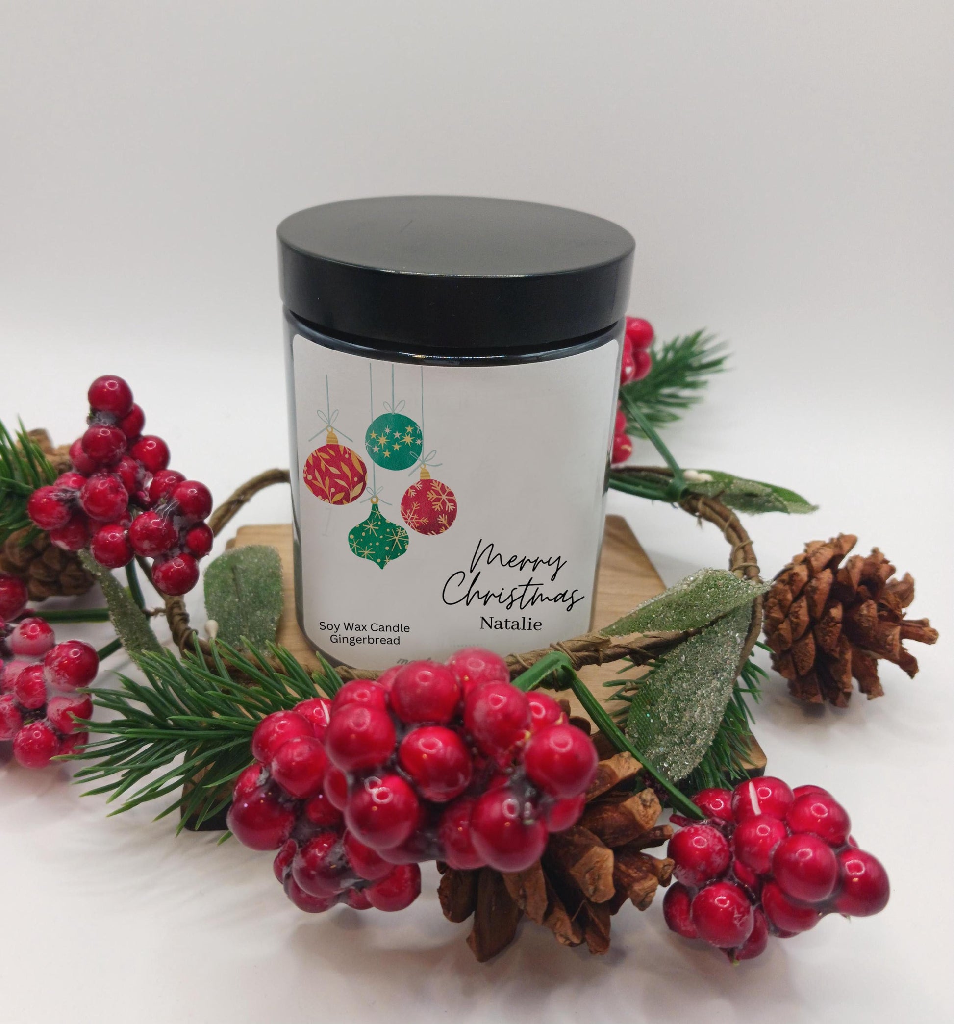 Candle with a 'Merry Christmas' label surrounded by festive decorations on a white background