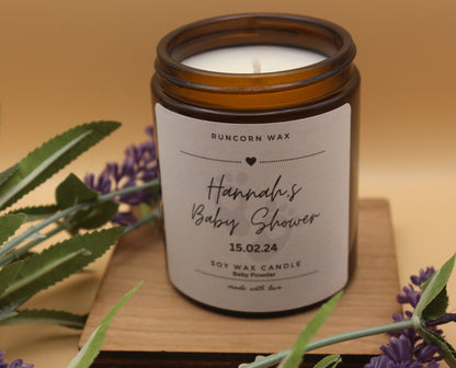 Candle in an amber jar with a personalized label on a wooden surface, surrounded by lavender flowers.