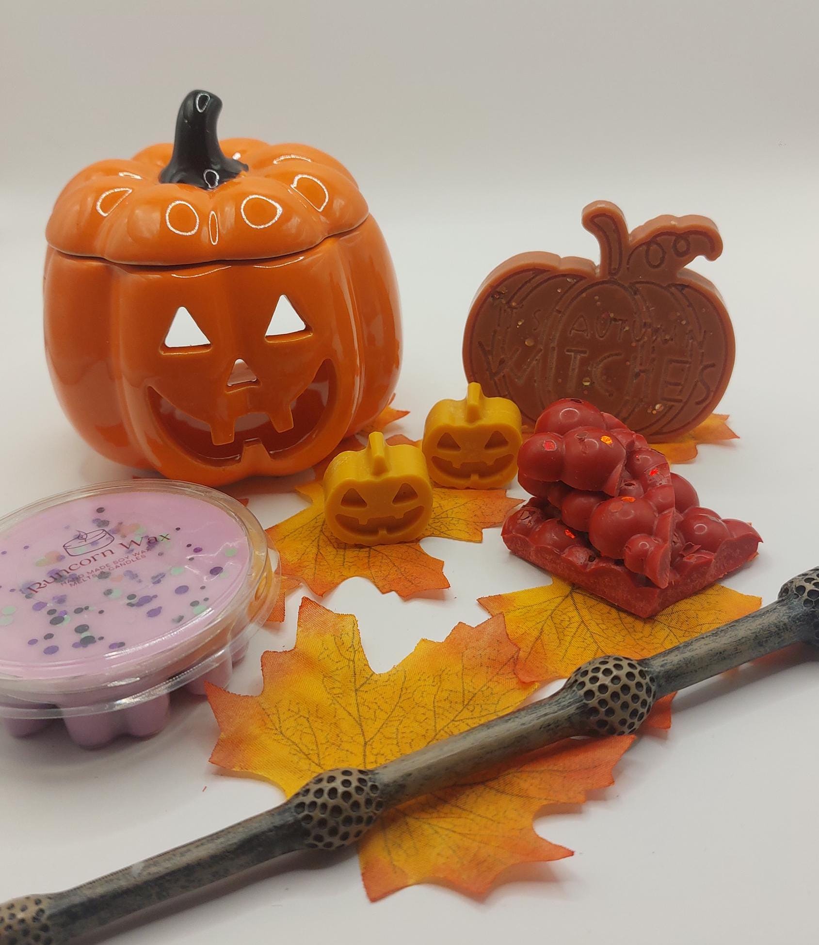Halloween-themed items including a jack-o'-lantern-shaped container, candles, and decorative elements on a white background.