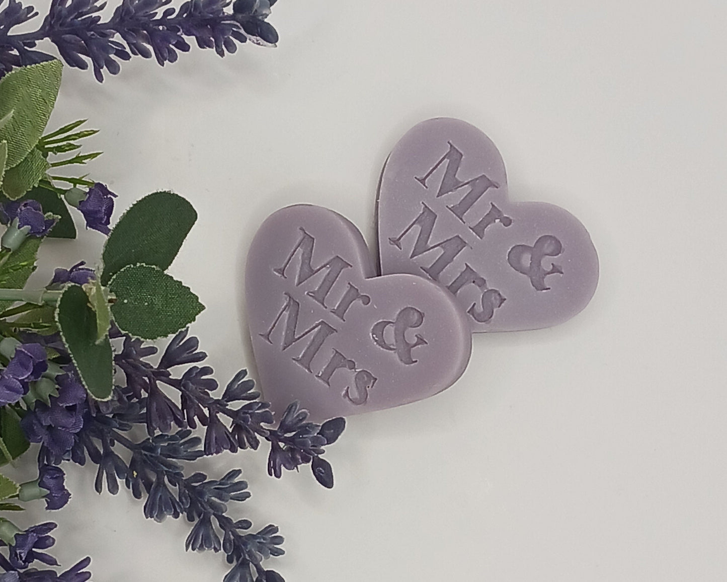 Two purple heart-shaped tokens with 'Mr & Mrs' text surrounded by lavender flowers on a light background