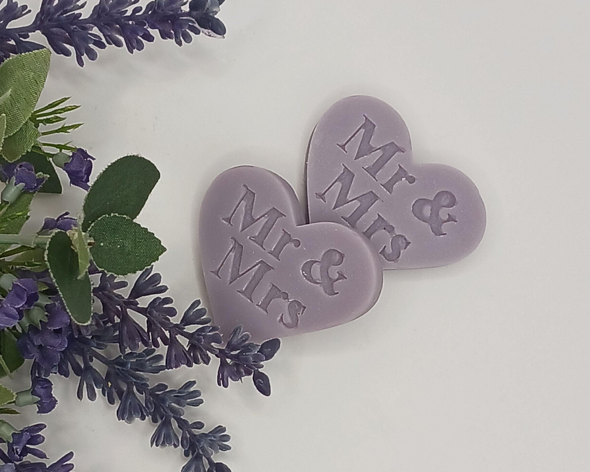 Two purple heart-shaped tokens with 'Mr & Mrs' text surrounded by lavender flowers on a light background