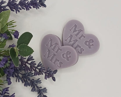Two purple heart-shaped tokens with 'Mr & Mrs' text surrounded by lavender flowers on a light background