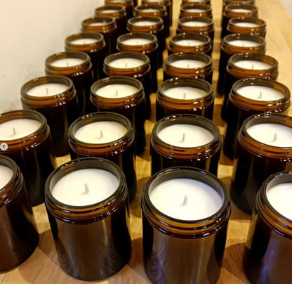 Multiple small candles in brown jars arranged on a wooden surface.