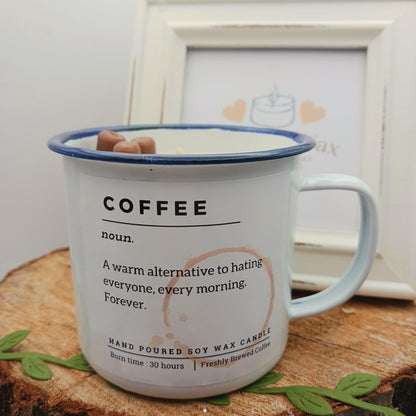 Candle in a mug with 'COFFEE' definition text on a wooden surface.