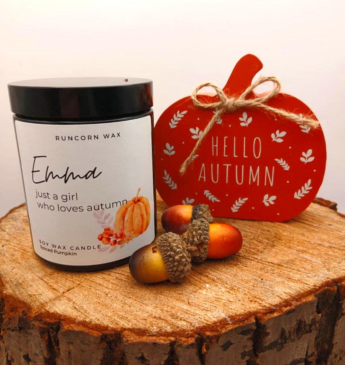 Candle labeled 'Emma' with decorative elements on a wooden surface