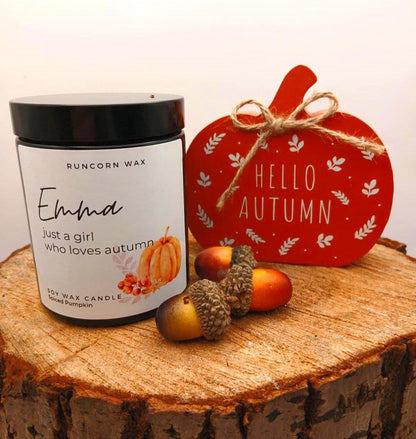 Candle labeled 'Emma' with decorative elements on a wooden surface