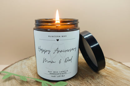Candle with a 'Happy Anniversary Mum & Dad' label on a wooden surface