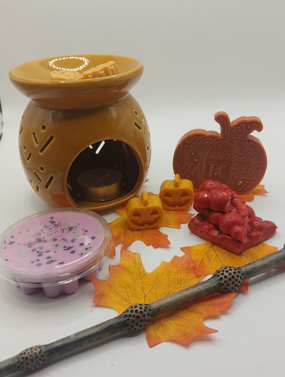 Aromatherapy diffuser with wicks, Halloween-themed candles, and decorative leaves on a white background.