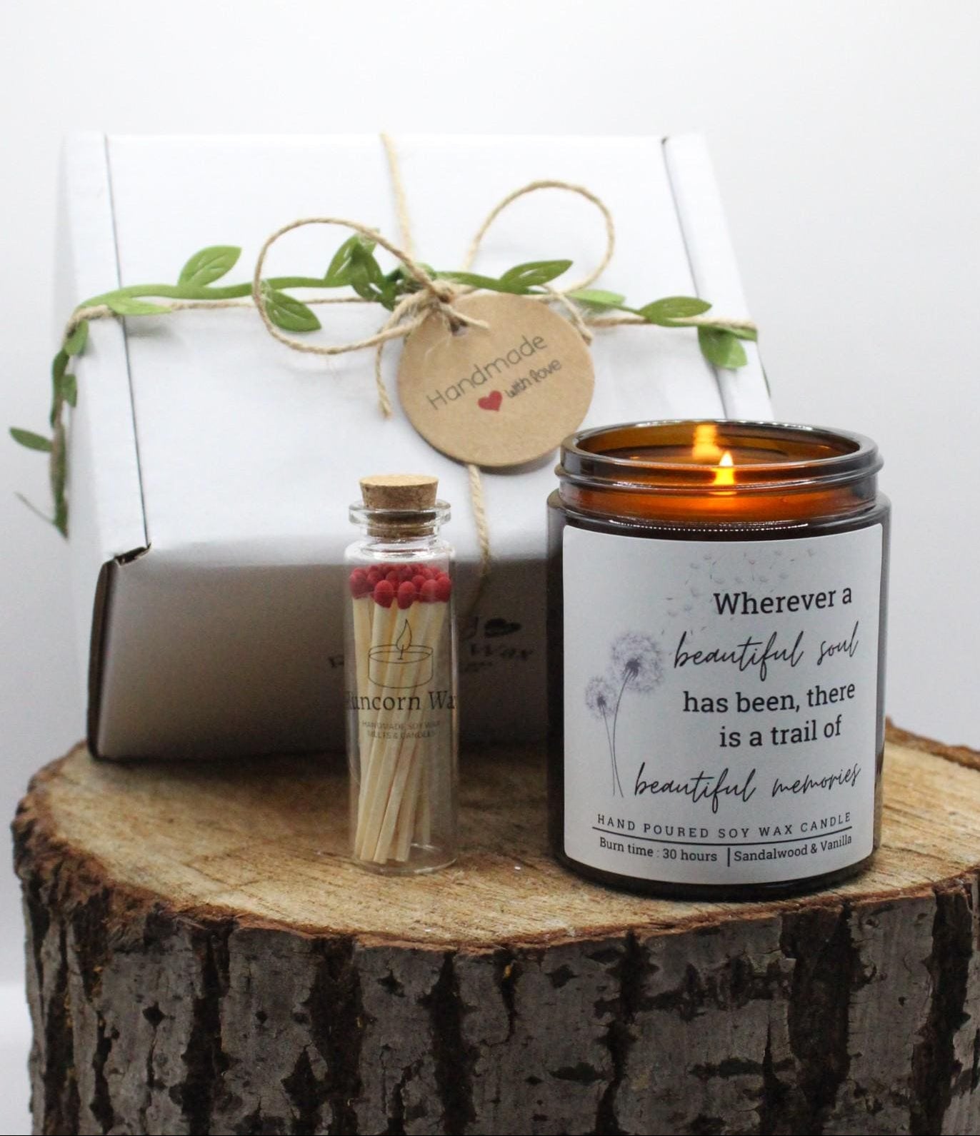 Candle with a quote on a wooden stump next to a small bottle and gift box. bereavement loss sorry sympathy gift