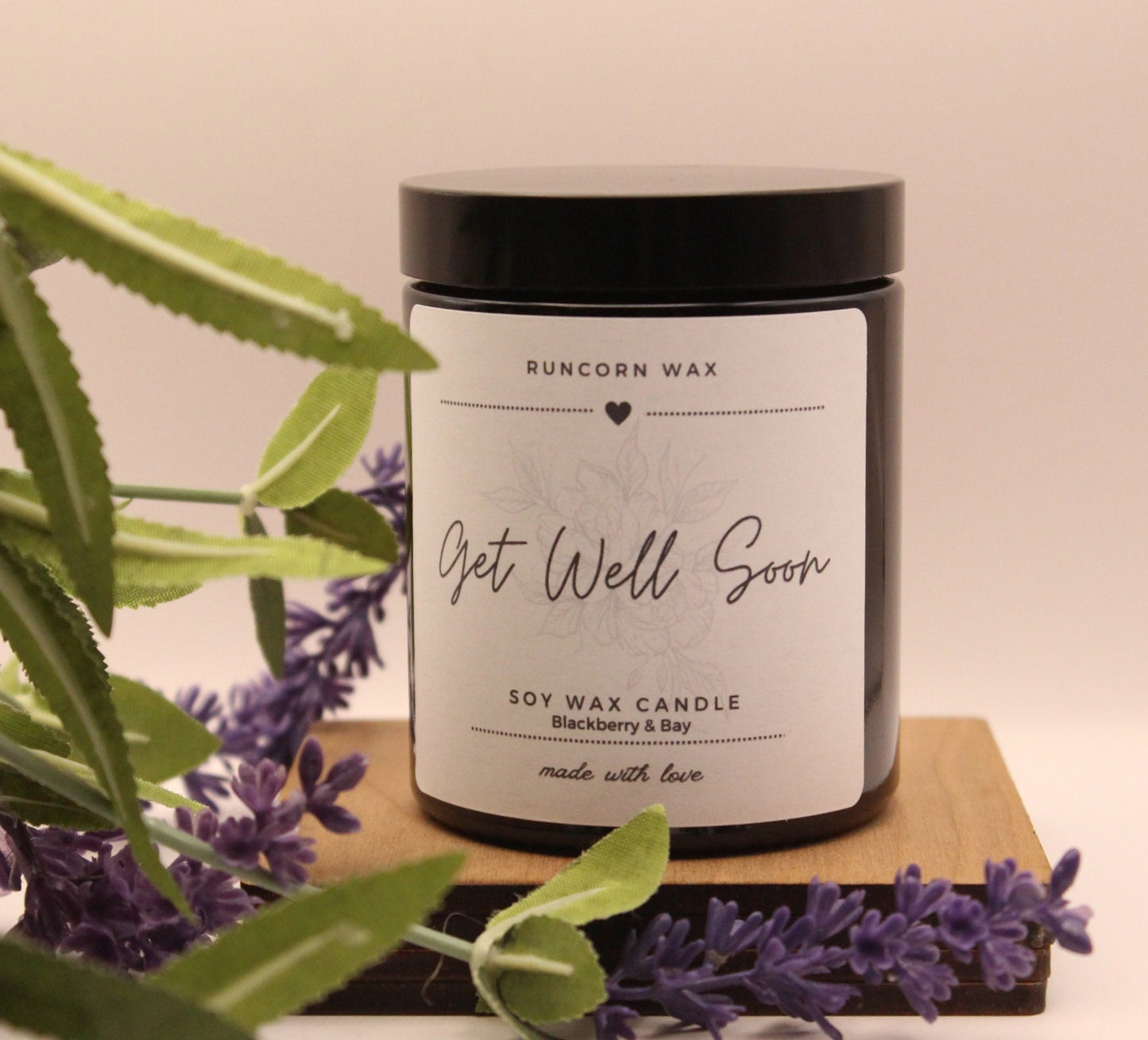 Candle labeled 'Get Well Soon' with lavender and greenery on a wooden board.