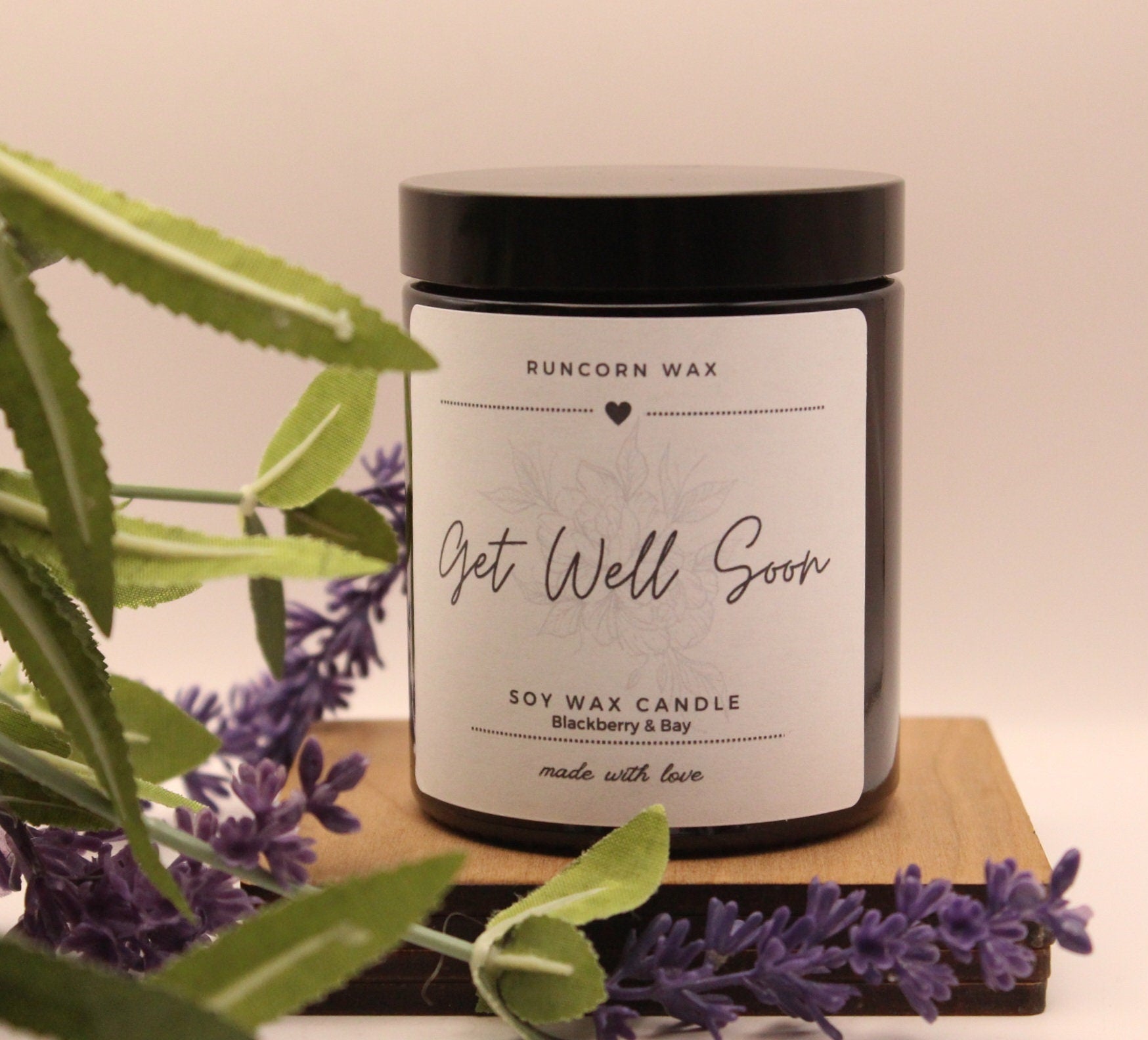Candle labeled 'Get Well Soon' with lavender and greenery on a wooden board.