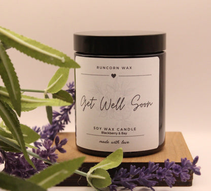 Candle labeled 'Get Well Soon' with lavender and greenery on a wooden board.