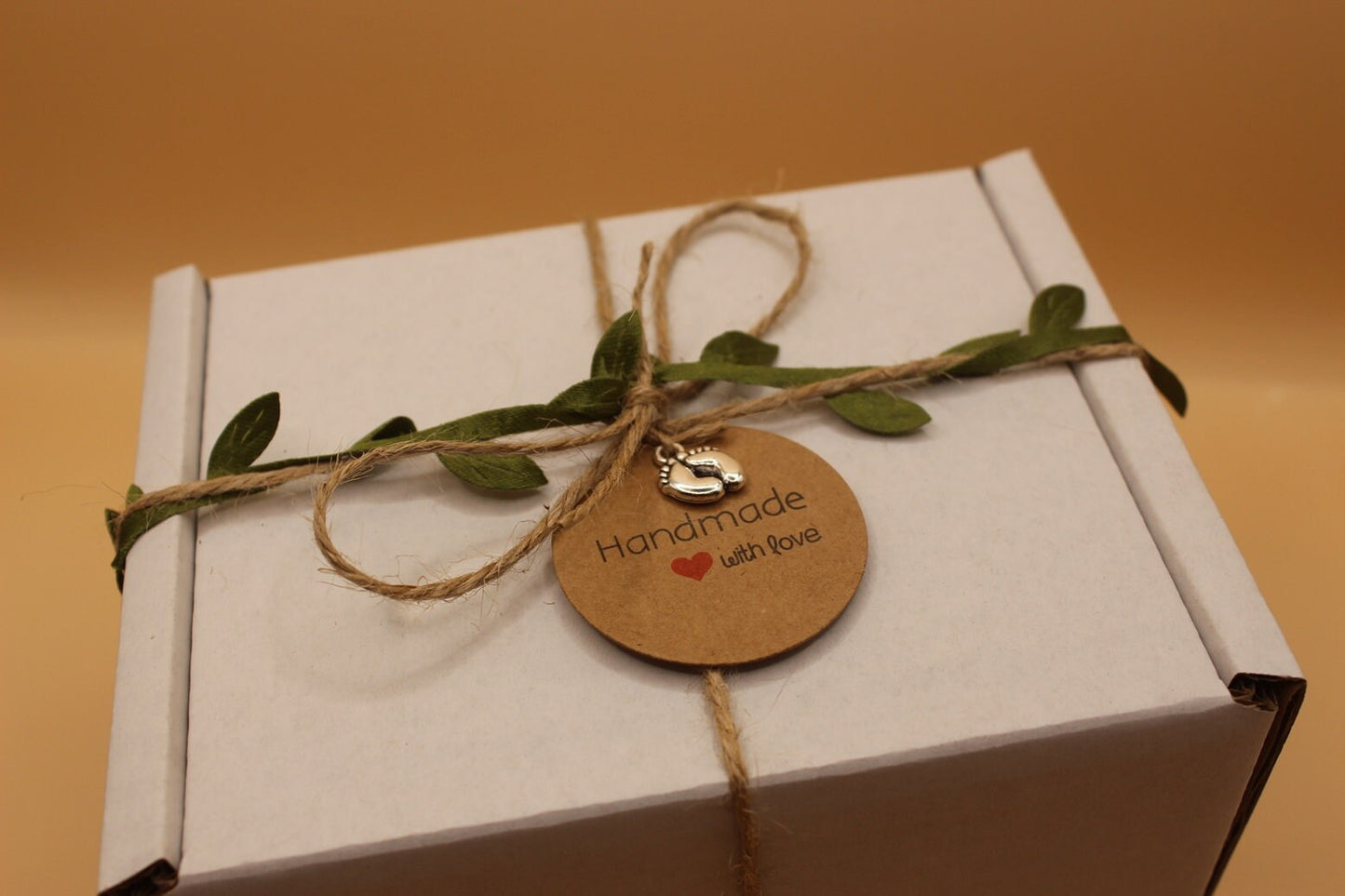 White box with string, leaves, and a 'Handmade with Love' tag on a brown background