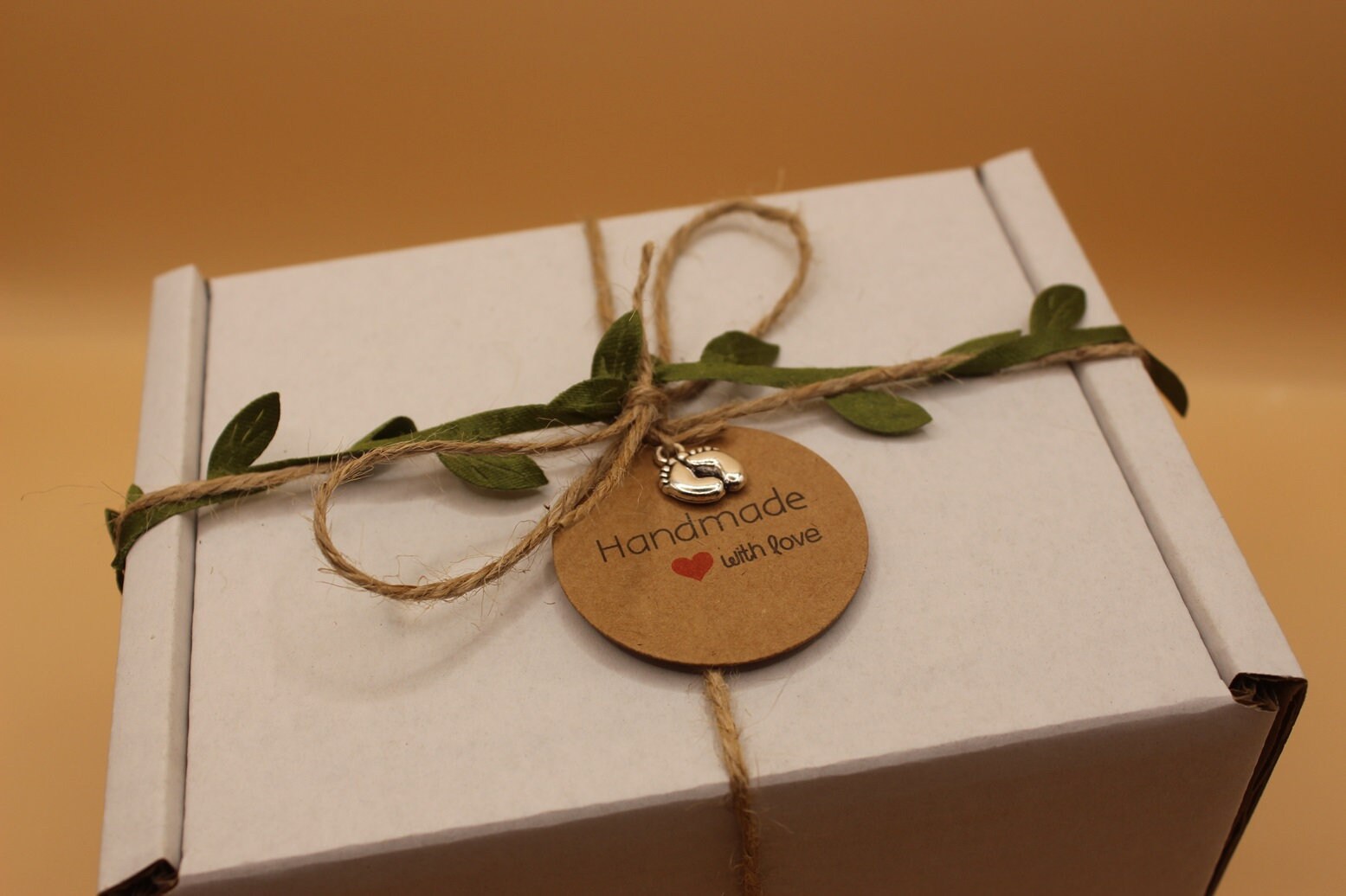 White box with string, leaves, and a 'Handmade with Love' tag on a brown background
