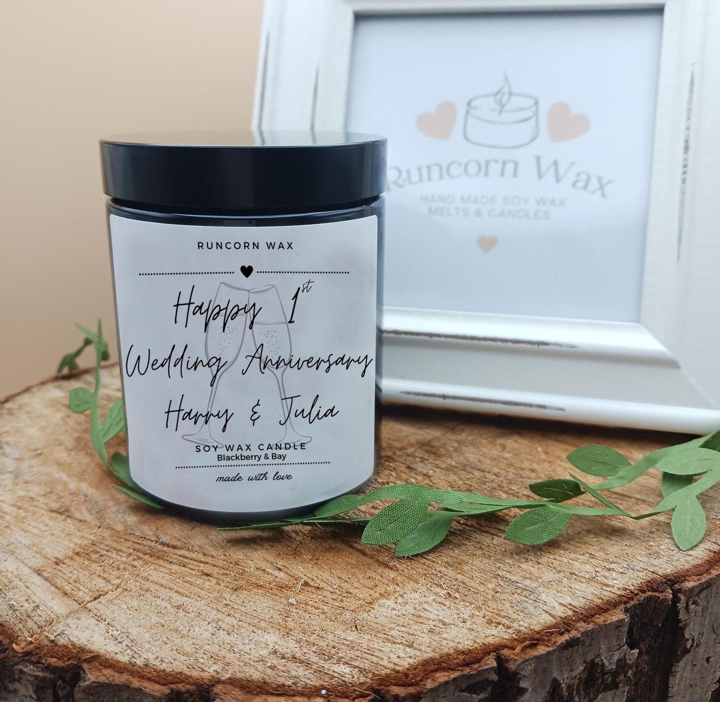 Personalized candle with 'Happy 1st Wedding Anniversary' text on a wooden surface with Runcorn Wax branding.