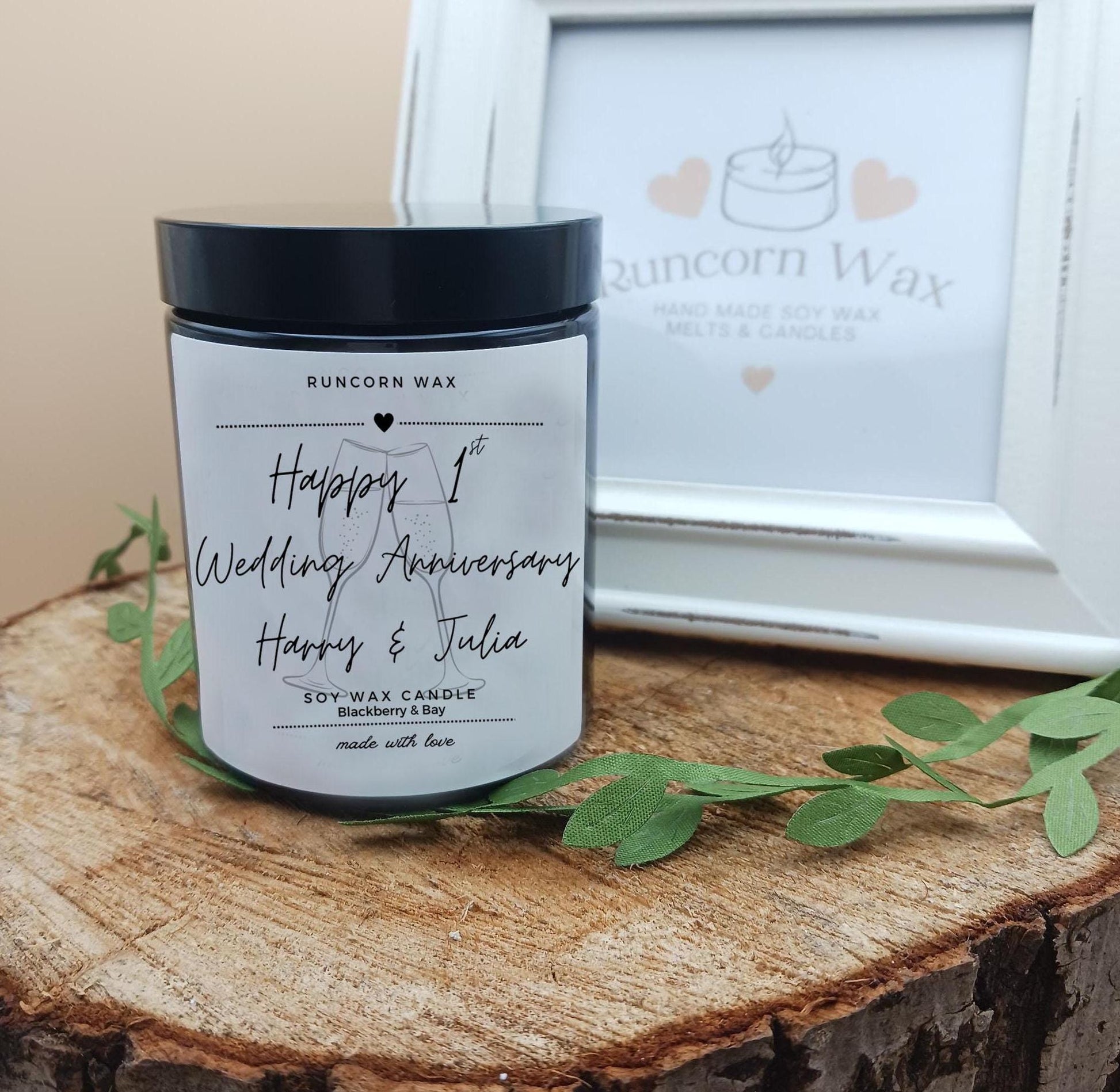 Personalized candle with 'Happy 1st Wedding Anniversary' text on a wooden surface with Runcorn Wax branding.