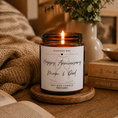 Candle with a 'Happy Anniversary Mum & Dad' label on a wooden surface.