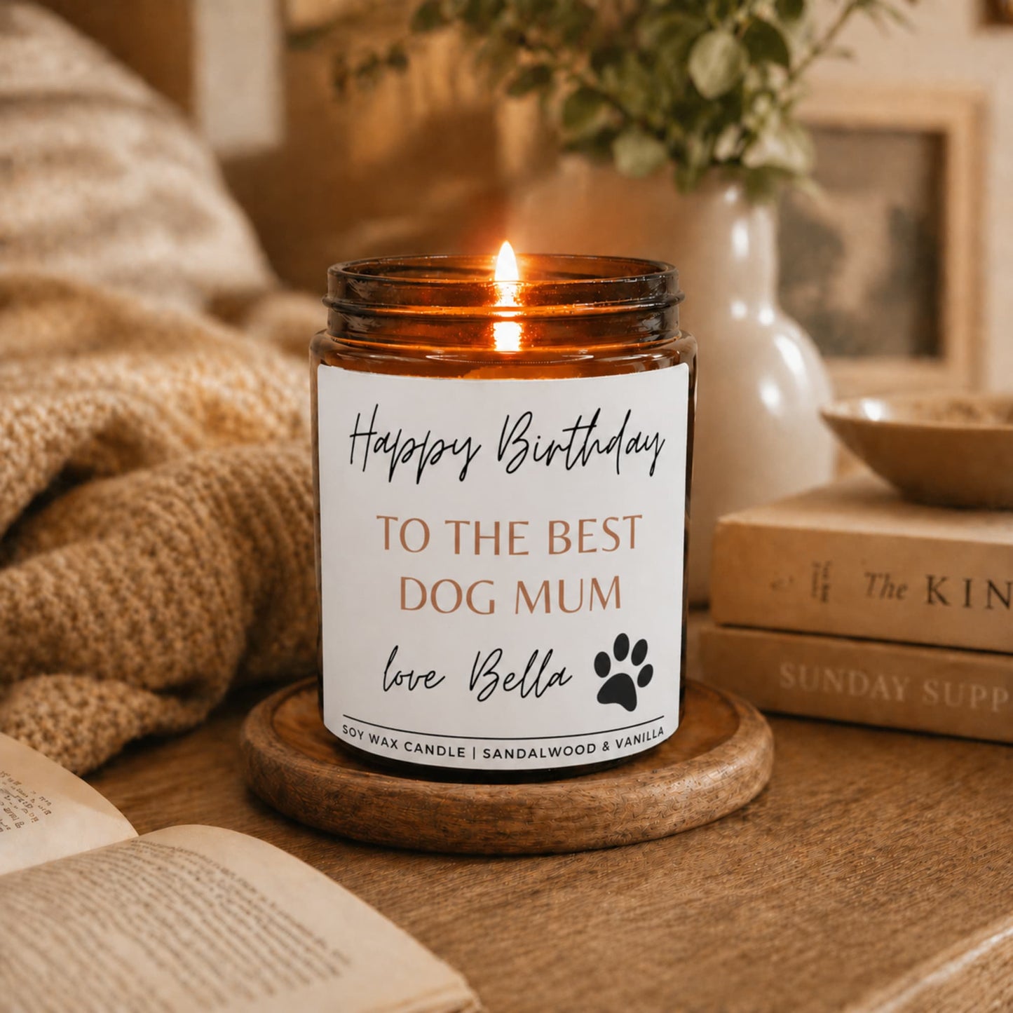 Candle in an amber jar with a 'Happy Birthday to the best dog mum' label on a wooden coaster.
