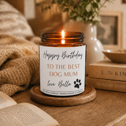 Candle in an amber jar with a 'Happy Birthday to the best dog mum' label on a wooden coaster.