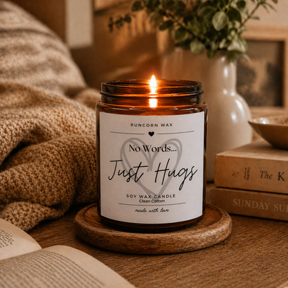 Candle with a label reading 'No Words... Just Hugs' on a wooden surface.
