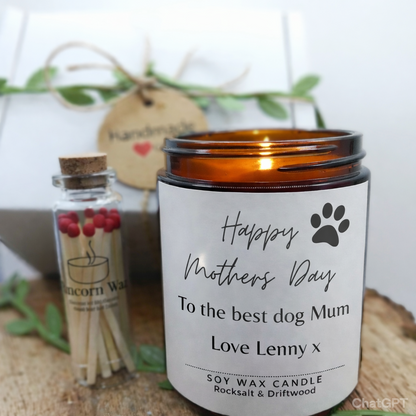 mothers day candle gift set from runcorn wax featuring label happy mothers day to the best dog mum love with matches and decorative present Candle with a label for Mother's Day, matches, and a small bottle on a wooden surface.