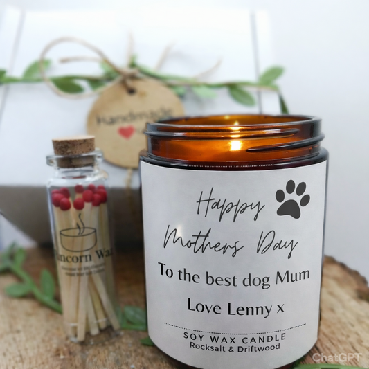 mothers day candle gift set from runcorn wax featuring label happy mothers day to the best dog mum love with matches and decorative present Candle with a label for Mother's Day, matches, and a small bottle on a wooden surface.