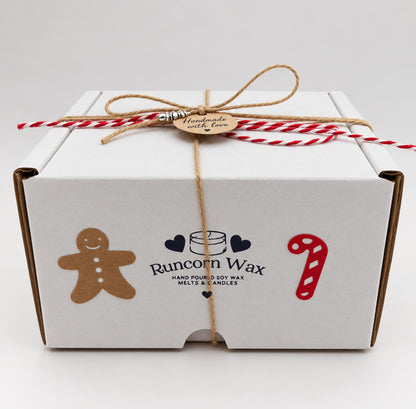 A white gift box tied with brown twine and red and white twine. The box has a gingerbread man sticker, a candy cane sticker, and a sticker that says "Runcorn Wax Hand Made Soy Wax Melts & Candles".