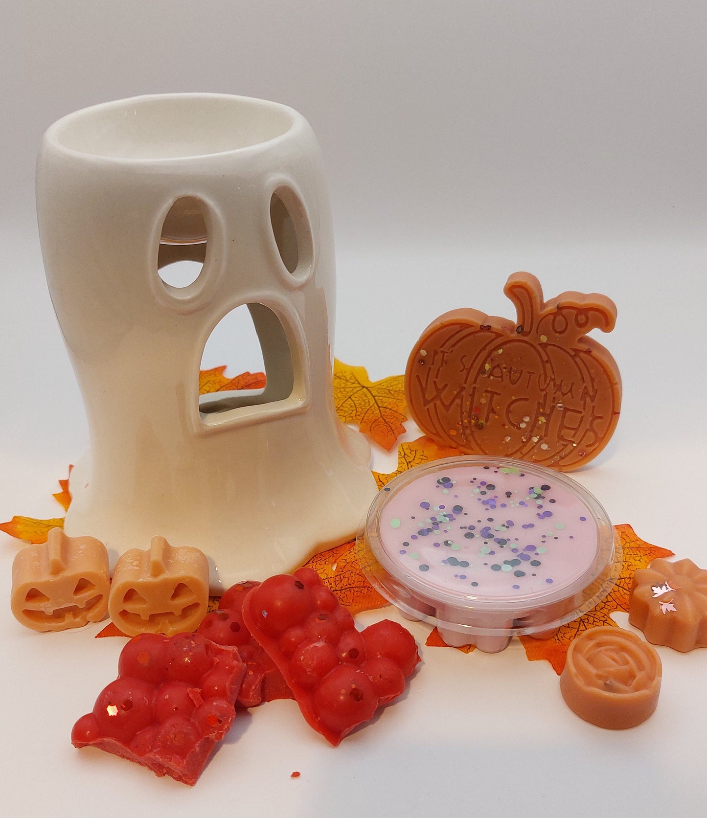 Decorative wax melts and a ceramic holder on a white background