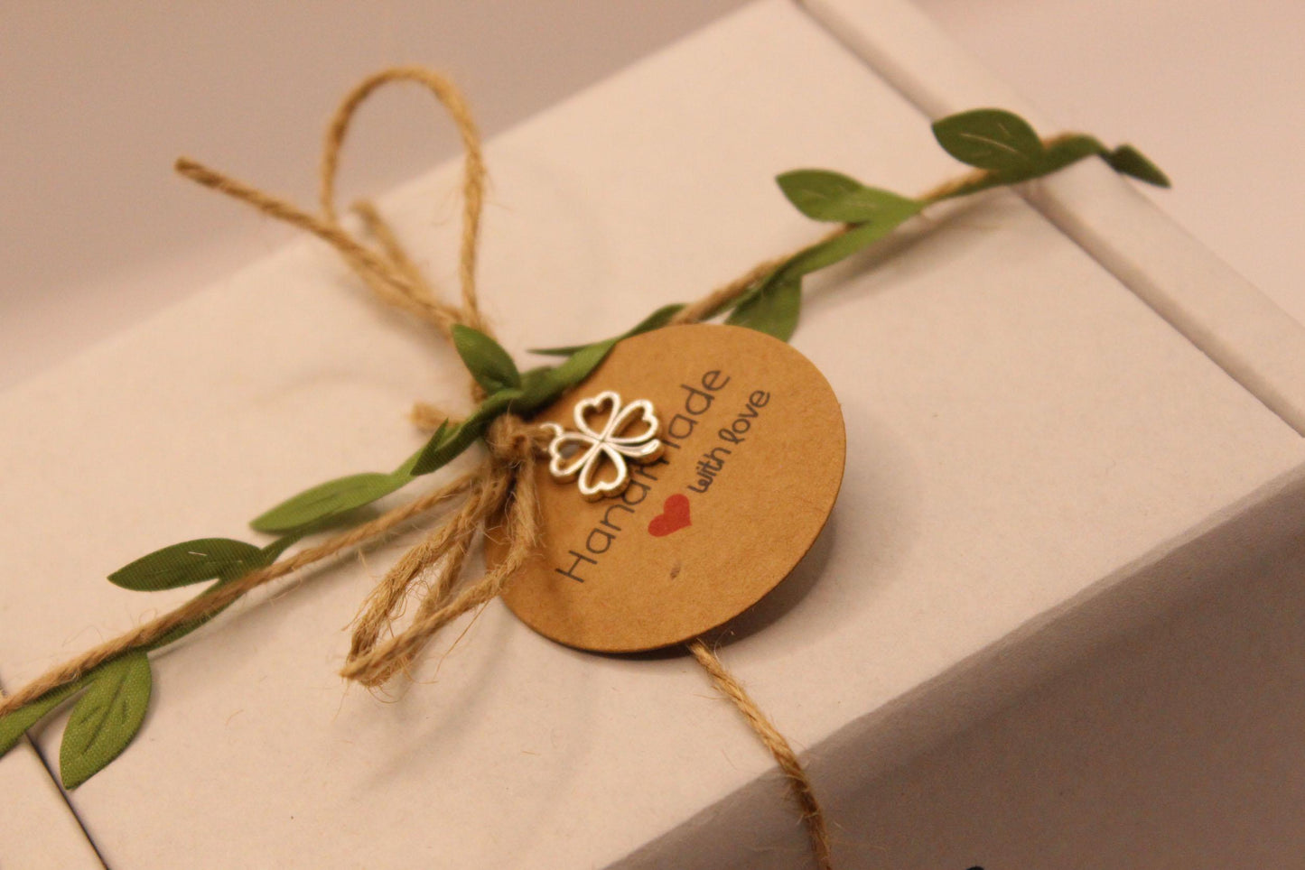 Gift box with string, leaves, and a decorative tag on a white surface