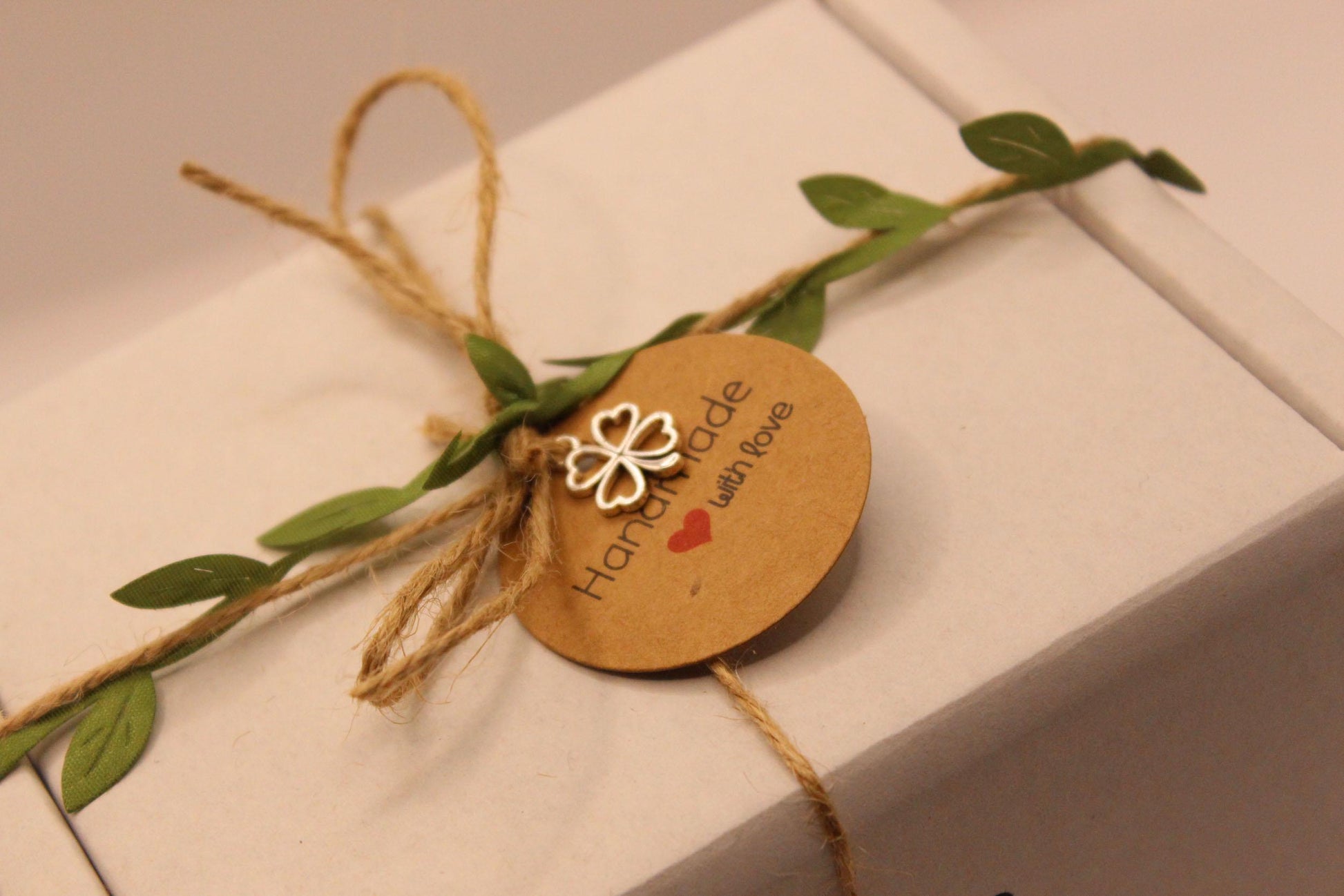 Gift box with string, leaves, and a decorative tag on a white surface