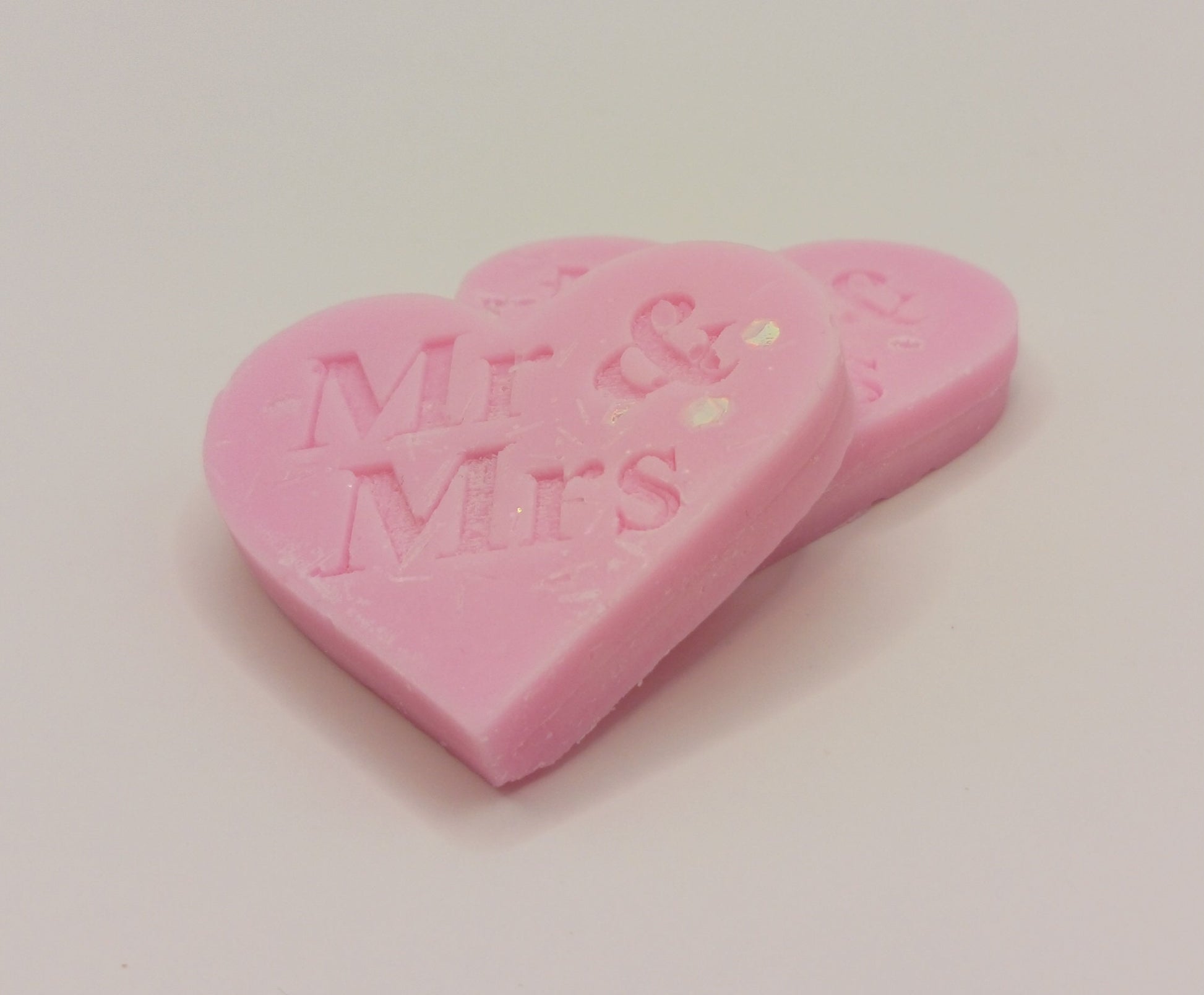 Pink heart-shaped candy with 'Mr & Mrs' embossed on a light gray background