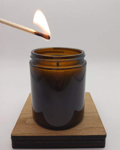 Amber glass candle being lit with a wooden match on a white background