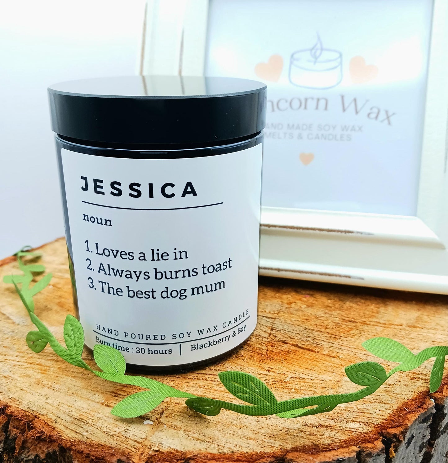Candle labeled 'Jessica' with a humorous definition on a wooden surface.