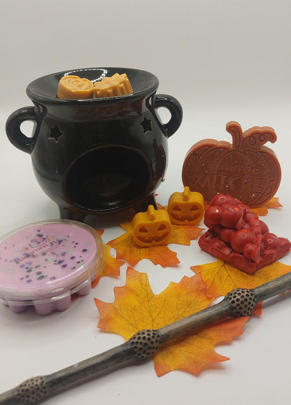 Black ceramic burner with wax melts shaped like pumpkins, a leaf, and a wand on a white background.