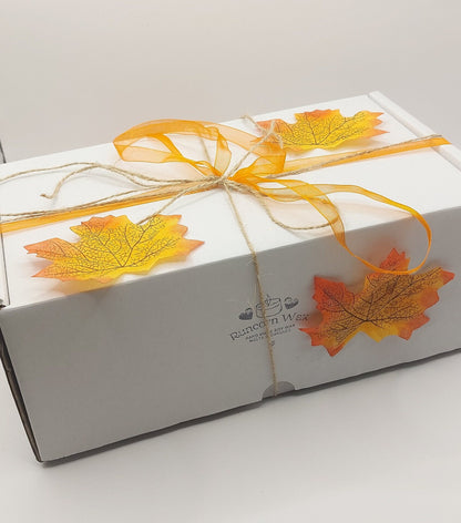 Gift box with autumn leaf decorations and a bow on a white background