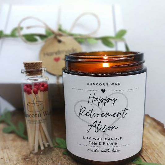 Personalized soy wax candle  happy retirement custom name with a small bottle of candles on a wooden surface.